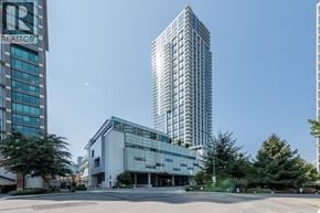 Burnaby apartment for rent - A modern building with a glass facade stands in front of a tall tree.