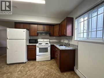 Vancouver apartment for rent - A kitchen with brown cabinets and a white refrigerator.