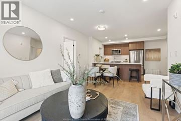 Windsor condo for rent - A modern living room with a grey sofa, a round table with a vase on it, and a kitchen area in the background.