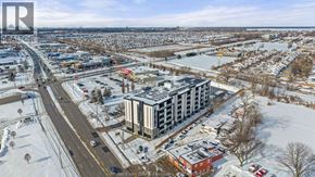 Windsor condo for rent - A large building with a flat roof is surrounded by a parking lot.