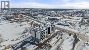 Windsor condo for rent - A winter scene with a large building in the center and a parking lot in the foreground.