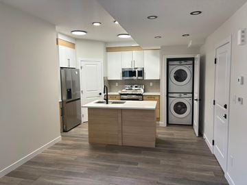 Edmonton apartment for rent - A modern kitchen with a refrigerator, sink, and washing machine.