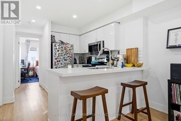 Toronto (Niagara) townhouse for rent - A kitchen with white cabinets and a white counter top with two stools in front.