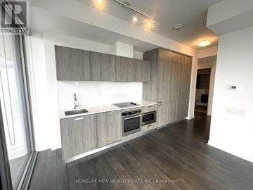 Toronto (Church-Yonge Corridor) condo for rent - A modern kitchen with wooden cabinets and a white countertop.