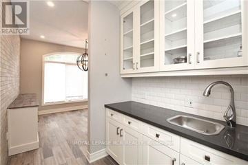 Newmarket (Stonehaven-Wyndham) townhouse for rent - A kitchen with white cabinets and a black countertop.