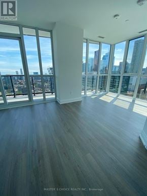 Toronto (Church-Yonge Corridor) condo for rent - A spacious room with wooden floors and large windows overlooking a city skyline.