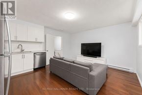 Toronto (O'connor-Parkview) townhouse for rent - A living room with a grey couch and a television on a white stand.