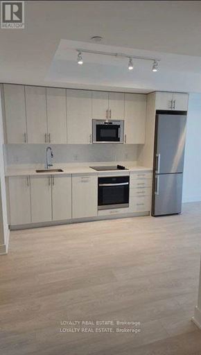 Oshawa (Windfields) condo for rent - A modern kitchen with white cabinets and stainless steel appliances.