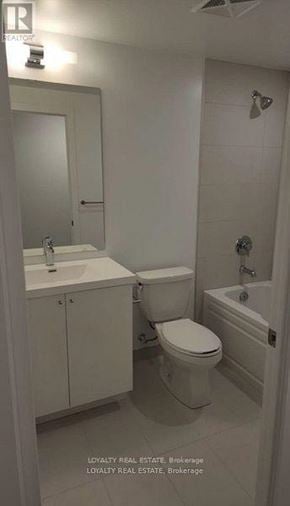 Oshawa (Windfields) condo for rent - A white bathroom with a toilet, sink, and mirror.