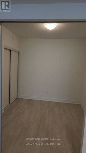Oshawa (Windfields) condo for rent - A room with a wooden floor and a white wall with a door.