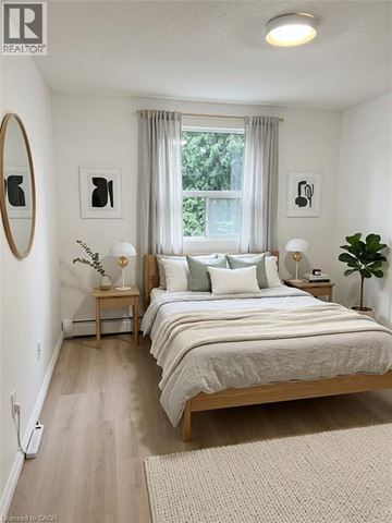 Brantford condo for rent - A bedroom with a large bed and a window with curtains.