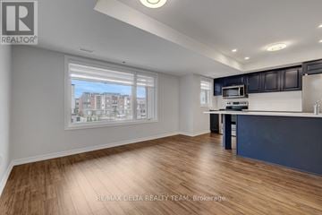Ottawa townhouse for rent - A spacious room with wooden flooring and a kitchen area with a microwave and oven.