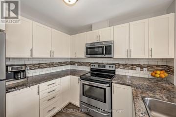 Ottawa condo for rent - A kitchen with white cabinets and a stove top oven.