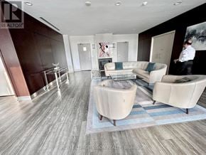 Toronto (Bayview Village) condo for rent - A living room with a glass coffee table and a man standing in the background.