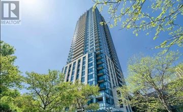 Toronto (Banbury-Don Mills) condo for rent - A tall building with many windows is surrounded by trees.