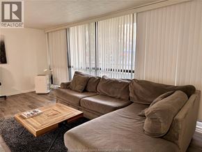 Windsor condo for rent - A living room with a couch, coffee table, and window with blinds.