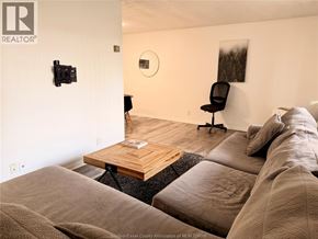 Windsor condo for rent - A living room with a couch, chair, and a camera on the wall.