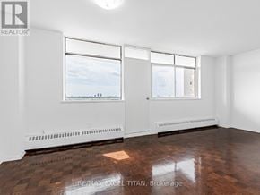 Toronto (Weston) condo for rent - A large, empty room with a view of the city through the windows.
