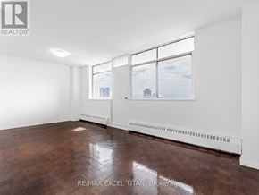Toronto (Weston) condo for rent - A large, empty room with a view of the city through the windows.