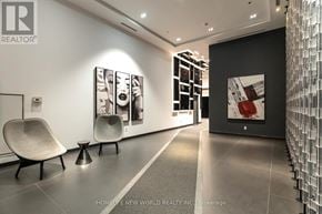Toronto (Waterfront Communities) condo for rent - A modern office lobby with a glass wall and two chairs.