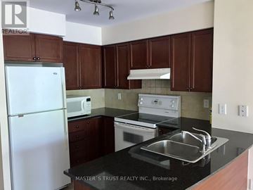 Toronto (Niagara) condo for rent - A kitchen with brown cabinets and a white refrigerator.