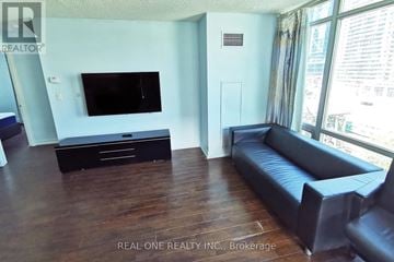 Toronto (Waterfront Communities) condo for rent - A living room with a black leather couch and a flat screen TV.