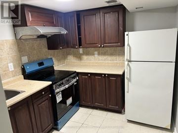 Brampton (Fletcher's Creek Village) apartment for rent - A kitchen with brown cabinets and a white refrigerator.