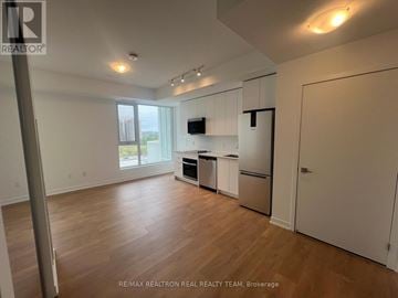 Vaughan (Concord) condo for rent - A spacious kitchen with white cabinets and a wooden floor.