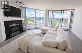 Vancouver apartment for rent - A living room with a fireplace and a large window overlooking a body of water.