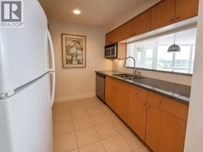 Vancouver apartment for rent - A kitchen with a white fridge, brown cabinets, and a painting on the wall.