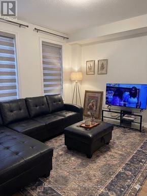 Tillsonburg townhouse for rent - A black leather sofa and ottoman in a living room with a flat screen TV.