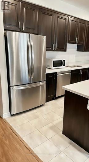 Tillsonburg townhouse for rent - A kitchen with a stainless steel refrigerator and brown cabinets.