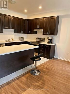 Tillsonburg townhouse for rent - A kitchen with dark brown cabinets and a white countertop.