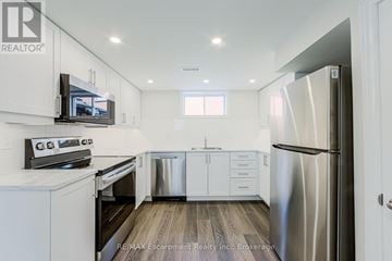 Hamilton (Macassa) duplex for rent - A kitchen with white cabinets and a stainless steel refrigerator.