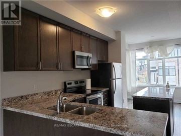 Hamilton (Ancaster) townhouse for rent - A kitchen with brown cabinets and a granite countertop.
