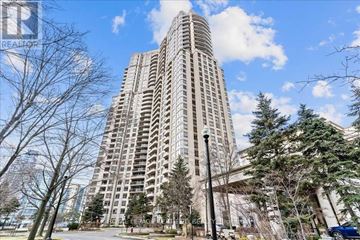 Mississauga (Hurontario) condo for rent - A tall residential building with a blue sky and clouds in the background.