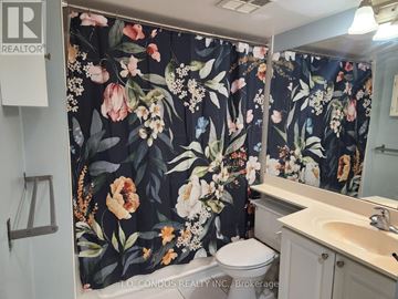 Toronto (Willowdale East) condo for rent - A bathroom with floral shower curtain and a toilet.