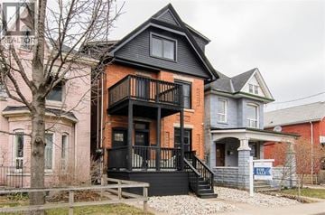 Hamilton apartment for rent - A house with a black front porch and a tree in front.