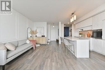 Toronto (Mount Pleasant West) condo for rent - A modern kitchen and living room with a grey sofa and wooden floors.