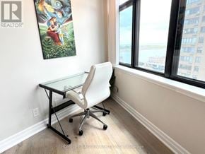 Toronto (Waterfront Communities) condo for rent - A room with a desk and a chair with a window in the background.