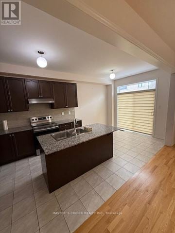 Brampton (Northwest Brampton) apartment for rent - A kitchen with dark brown cabinets and a granite countertop.