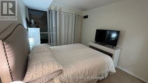 Mississauga (Erin Mills) condo for rent - A bedroom with a bed, a television, and a window with curtains.