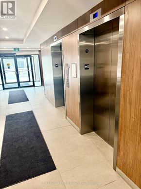 Windsor condo for rent - A hallway with two elevators and a door leading outside.