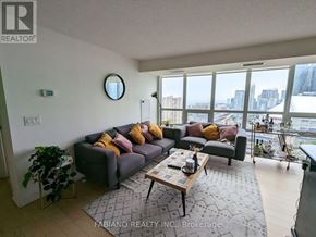 Toronto (Waterfront Communities) condo for rent - A living room with a grey couch and a coffee table in front of a large window.