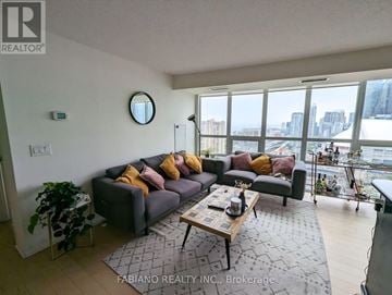 Toronto (Waterfront Communities) condo for rent - A living room with a grey couch and a coffee table in front of a large window.
