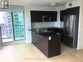 Toronto (Waterfront Communities) condo for rent - A kitchen with black cabinets and a stainless steel refrigerator.