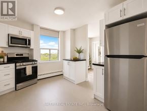 Toronto (Crescent Town) condo for rent - A modern kitchen with white cabinets and stainless steel appliances.