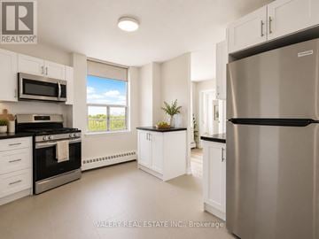 Toronto (Crescent Town) condo for rent - A modern kitchen with white cabinets and stainless steel appliances.