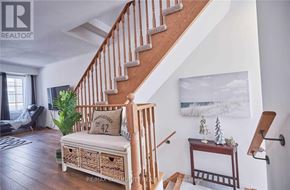 Oshawa (Windfields) townhouse for rent - A wooden staircase with a cushioned bench and a small table with a plant on it.