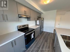 Brampton (Northwest Brampton) townhouse for rent - A kitchen with a stove top oven and a refrigerator.